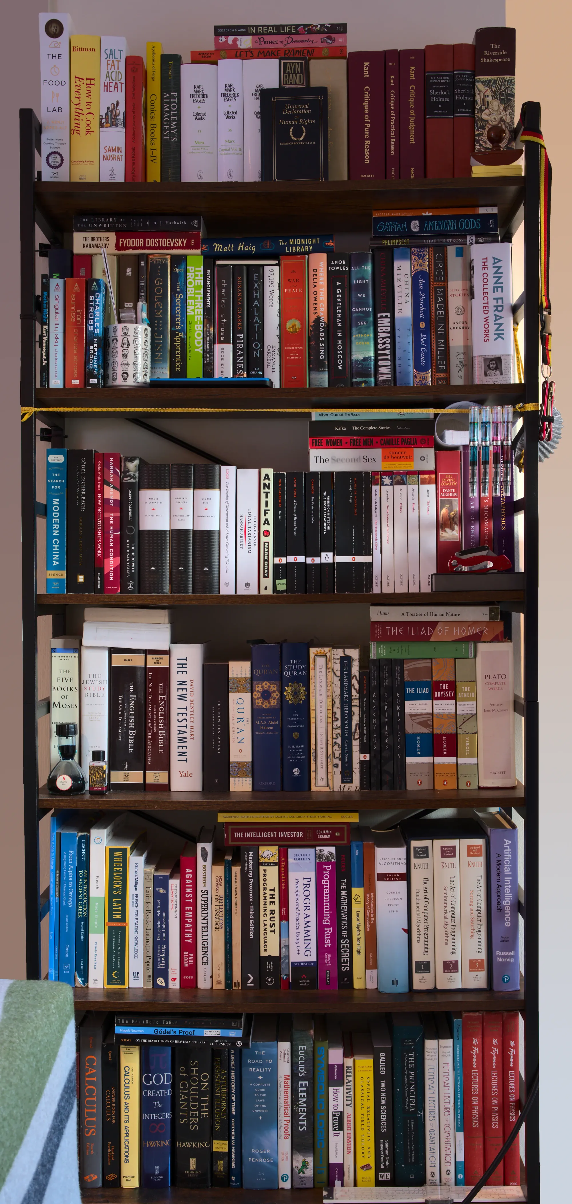 A photo of my bookshelf. There are 6 levels, all filled with books of many genres.